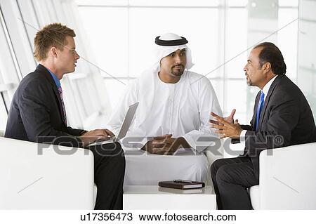 Three businessmen indoors with a laptop talking and smiling (high key/selective focus) View Large Photo Image Stock Image - Three businessmen indoors with a laptop talking and smiling (high key/selective focus). Fotosearch