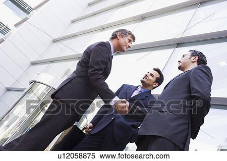 Three businessmen outdoors by building shaking hands and smiling (high key/selective focus) View Large Photo Image Stock Photography - Three businessmen outdoors by building shaking hands and smiling (high key/selective focus). Fotosearch
