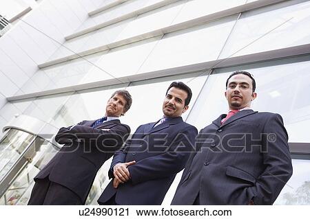 Three businessmen standing outdoors by building (high key/selective focus) View Large Photo Image Stock Image - Three businessmen standing outdoors by building (high key/selective focus). Fotosearch