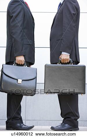 Two businessmen holding briefcases outdoors View Large Photo Image Stock Image - Two businessmen holding briefcases outdoors. Fotosearch