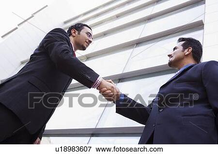 Two businessmen outdoors by building shaking hands (high key/selective focus) View Large Photo Image Stock Photo - Two businessmen outdoors by building shaking hands (high key/selective focus). Fotosearch