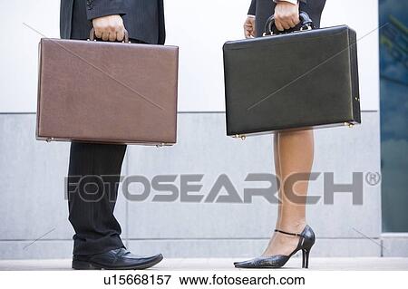 Stock Photo - Two businesspeople holding briefcases outdoors. Fotosearch
