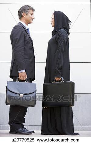 Two businesspeople standing outdoors with briefcases smiling View Large Photo Image Stock Photography - Two businesspeople standing outdoors with briefcases smiling. Fotosearch