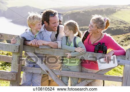 Family on cliffside path leaning on fence and smiling View Large Photo Image Picture - Family on cliffside path leaning on fence and smiling. Fotosearch