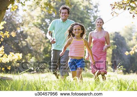 Family running outdoors smiling View Large Photo Image Stock Photograph - Family running outdoors smiling. Fotosearch