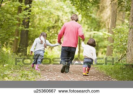 Father and daughters walking on path holding hands View Large Photo Image Stock Photo - Father and daughters walking on path holding hands. Fotosearch