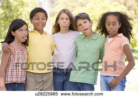 Stock Photography - Five young friends standing outdoors making funny faces. Fotosearch