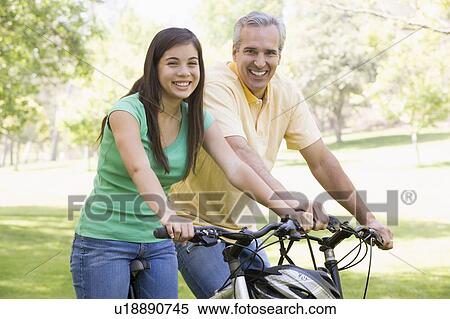 Man and girl on bikes outdoors smiling View Large Photo Image Stock Photography - Man and girl on bikes outdoors smiling. Fotosearch