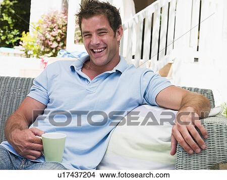 Man sitting on patio with coffee laughing View Large Photo Image Picture - Man sitting on patio with coffee laughing. Fotosearch