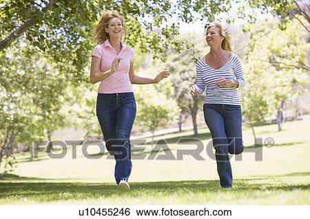 Stock Photograph - Two women running in park and smiling. Fotosearch