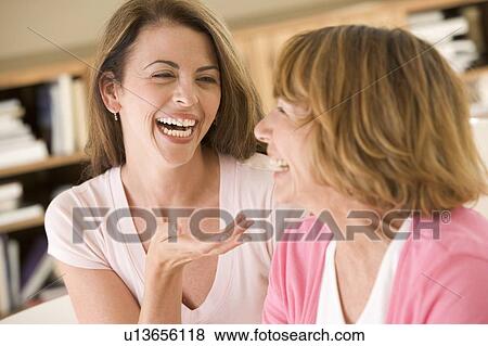 Stock Photo - Two women sitting in living room talking and laughing. Fotosearch