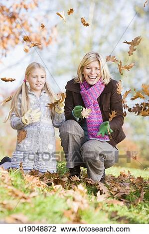 Woman and young girl outdoors in park playing in leaves and smiling (selective focus) View Large Photo Image Stock Image - Woman and young girl outdoors in park playing in leaves and smiling (selective focus). Fotosearch