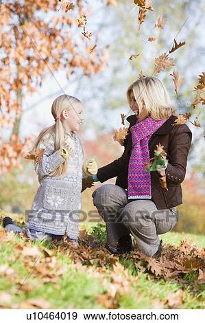 Woman and young girl outdoors in park playing in leaves and smiling (selective focus) View Large Photo Image Stock Photo - Woman and young girl outdoors in park playing in leaves and smiling (selective focus). Fotosearch