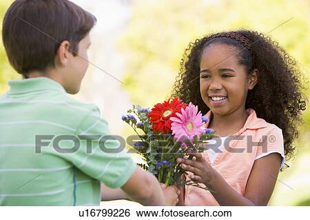 Young boy giving young girl flowers and smiling View Large Photo Image Stock Photograph - Young boy giving young girl flowers and smiling. Fotosearch