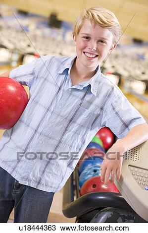 Young boy in bowling alley holding ball and smiling View Large Photo Image Stock Image - Young boy in bowling alley holding ball and smiling. Fotosearch