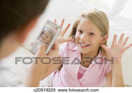 Young boy taking picture of smiling young girl with camera phone indoors View Large Photo Image Stock Photo - Young boy taking picture of smiling young girl with camera phone indoors. Fotosearch