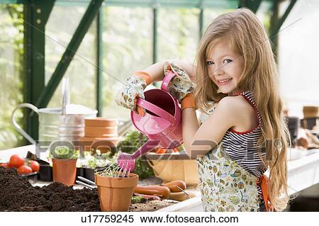 Young girl in greenhouse watering potted plant smiling View Large Photo Image Stock Photography - Young girl in greenhouse watering potted plant smiling. Fotosearch