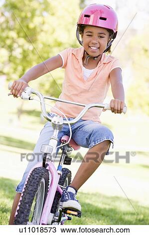 Young girl on bicycle outdoors smiling View Large Photo Image Stock Image - Young girl on bicycle outdoors smiling. Fotosearch
