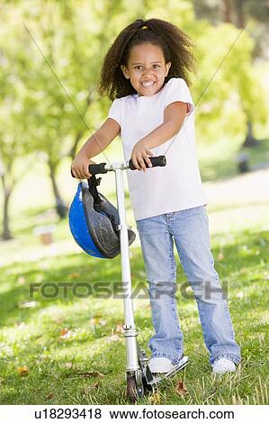 Young girl outdoors on scooter smiling View Large Photo Image Stock Photo - Young girl outdoors on scooter smiling. Fotosearch