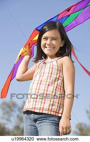 Stock Image - Young girl with kite outdoors smiling. Fotosearch