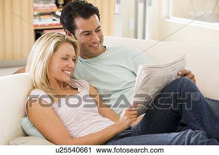 Couple in living room reading newspaper and smiling View Large Photo Image Stock Image - Couple in living room reading newspaper and smiling. Fotosearch