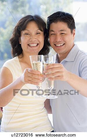 Couple toasting champagne and smiling View Large Photo Image Stock Photograph - Couple toasting champagne and smiling. Fotosearch