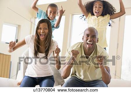 Picture - Family in living room cheering and smiling. Fotosearch