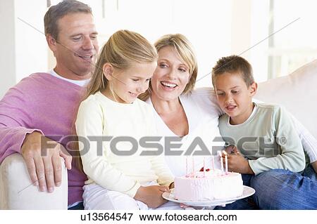 Stock Photo - Family in living room with cake smiling. Fotosearch