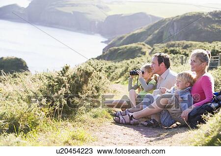 Stock Image - Family on cliffside path using binoculars and smiling. Fotosearch