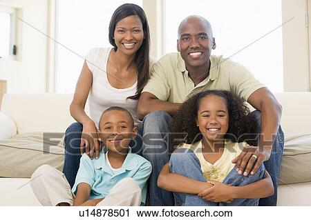 Stock Image - Family sitting in living room smiling. Fotosearch