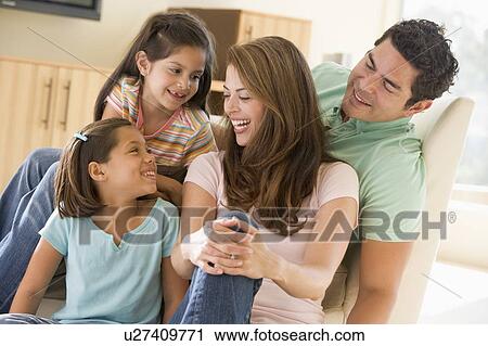 Stock Image - Family sitting in living room smiling. Fotosearch
