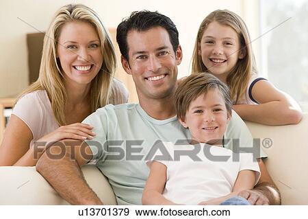 Stock Photo - Family sitting in living room smiling. Fotosearch