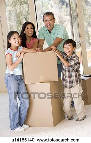 Stock Image - Family with boxes in new home smiling. Fotosearch