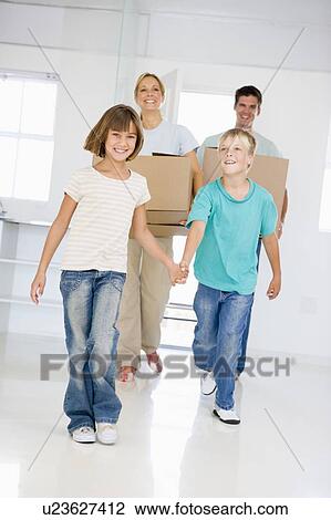 Stock Image - Family with boxes moving into new home smiling. Fotosearch