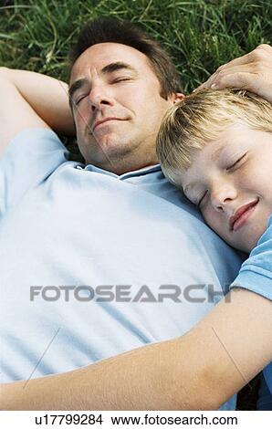Picture - Father and son lying outdoors sleeping. Fotosearch