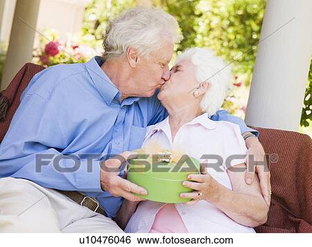 Husband giving wife gift on patio and kissing her View Large Photo Image Stock Photograph - Husband giving wife gift on patio and kissing her. Fotosearch