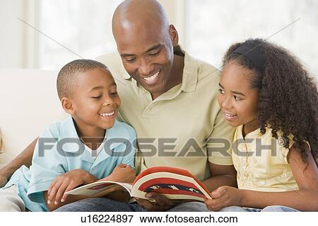 Man and two children sitting in living room reading book and smiling View Large Photo Image Stock Photo - Man and two children sitting in living room reading book and smiling. Fotosearch