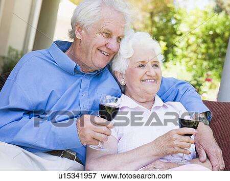 Stock Photo - Senior couple sitting outdoors having a glass of red wine. Fotosearch