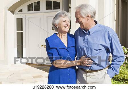 Stock Image - Senior couple standing outside their home. Fotosearch