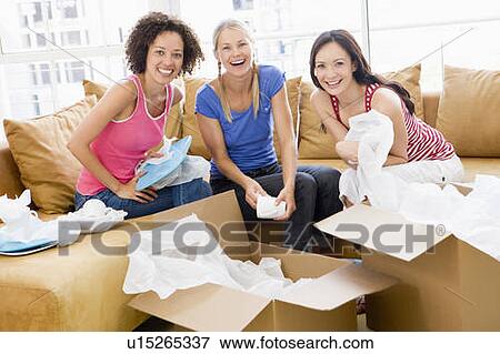 Three girl friends unpacking boxes in new home smiling View Large Photo Image Stock Photo - Three girl friends unpacking boxes in new home smiling. Fotosearch