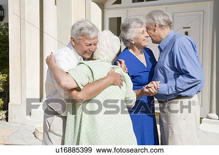 Stock Photo - Two senior couples greeting each other with open arms. Fotosearch