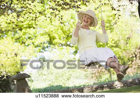 Woman in a swing outdoors smiling View Large Photo Image Stock Photo - Woman in a swing outdoors smiling. Fotosearch