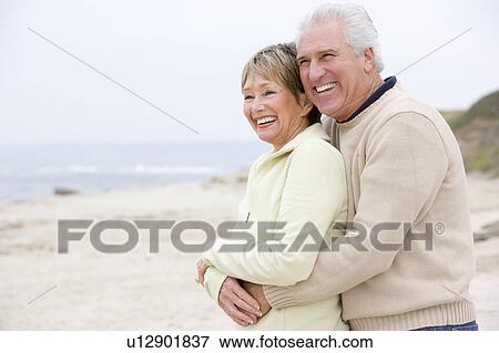 Stock Photo - Couple at the beach embracing and smiling. Fotosearch