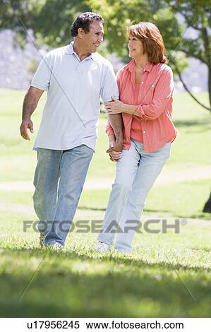 Couple holding hands outdoors by lake smiling View Large Photo Image Stock Photography - Couple holding hands outdoors by lake smiling. Fotosearch