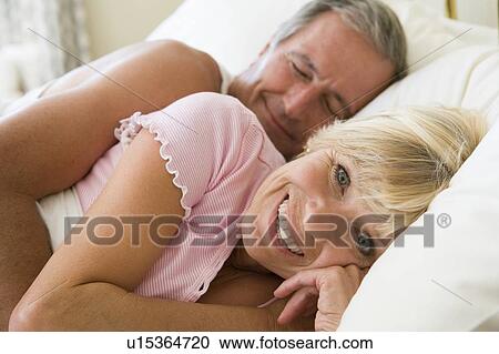 Couple lying in bed together smiling View Large Photo Image Stock Image - Couple lying in bed together smiling. Fotosearch