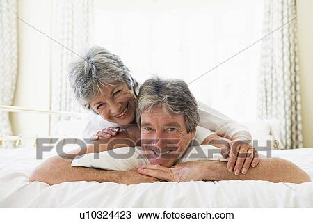 Couple lying on bed together smiling View Large Photo Image Stock Image - Couple lying on bed together smiling. Fotosearch