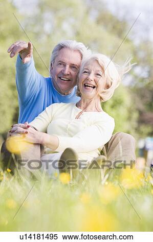 Stock Photography - Couple relaxing outdoors pointing and smiling. Fotosearch