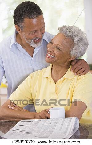 Stock Photo - Couple relaxing with a newspaper smiling. Fotosearch
