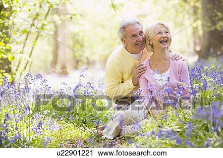 Stock Image - Couple sitting outdoors with flowers smiling. Fotosearch