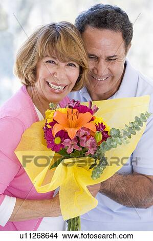 Husband and wife holding flowers and smiling View Large Photo Image Picture - Husband and wife holding flowers and smiling. Fotosearch